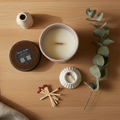 Candle, matches, eucalyptus leaves, and a book on a wooden surface