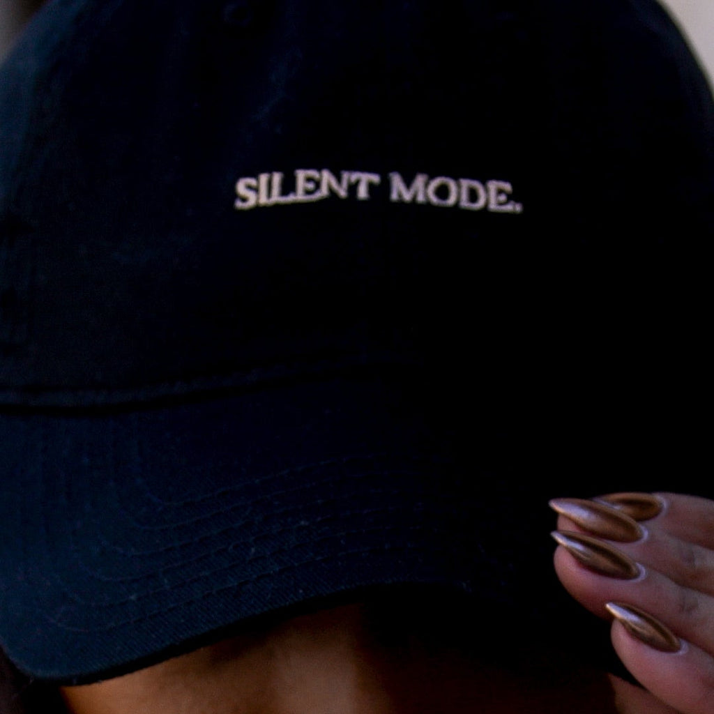 Person wearing a black cap with 'SILENT MODE' text, covering their face.