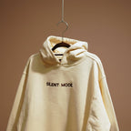 Beige oversized hoodie with 'SILENT MODE.' embroidered on the front and brand logo on the back.