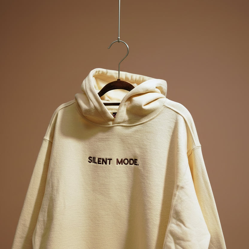 Beige oversized hoodie with 'SILENT MODE.' embroidered on the front and brand logo on the back.